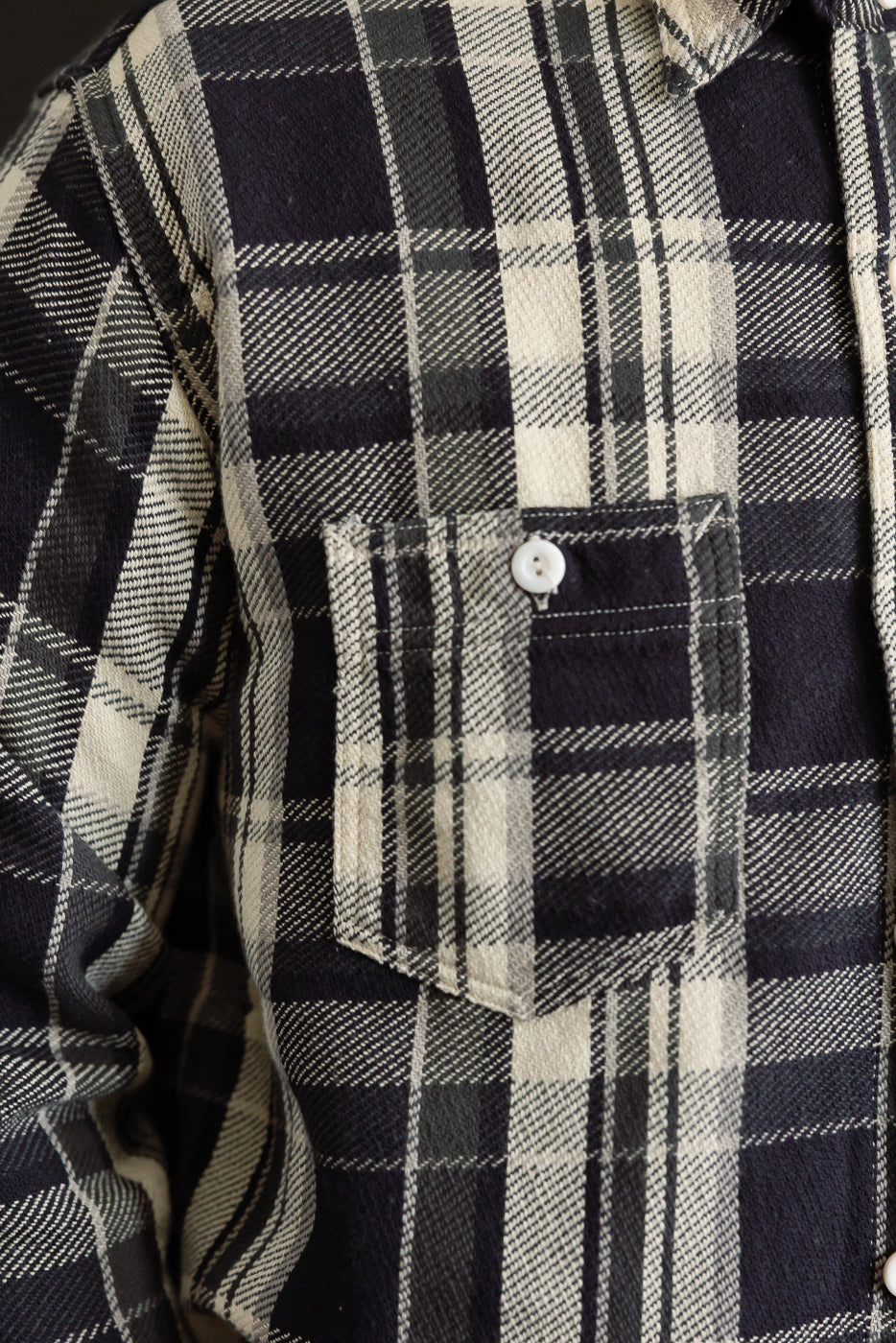 Close-up of front chest pocket on Post O’Alls St. Louis cotton flannel plaid shirt in grey, showing button detail and soft textured fabric, Dant contemporary casual apparel.