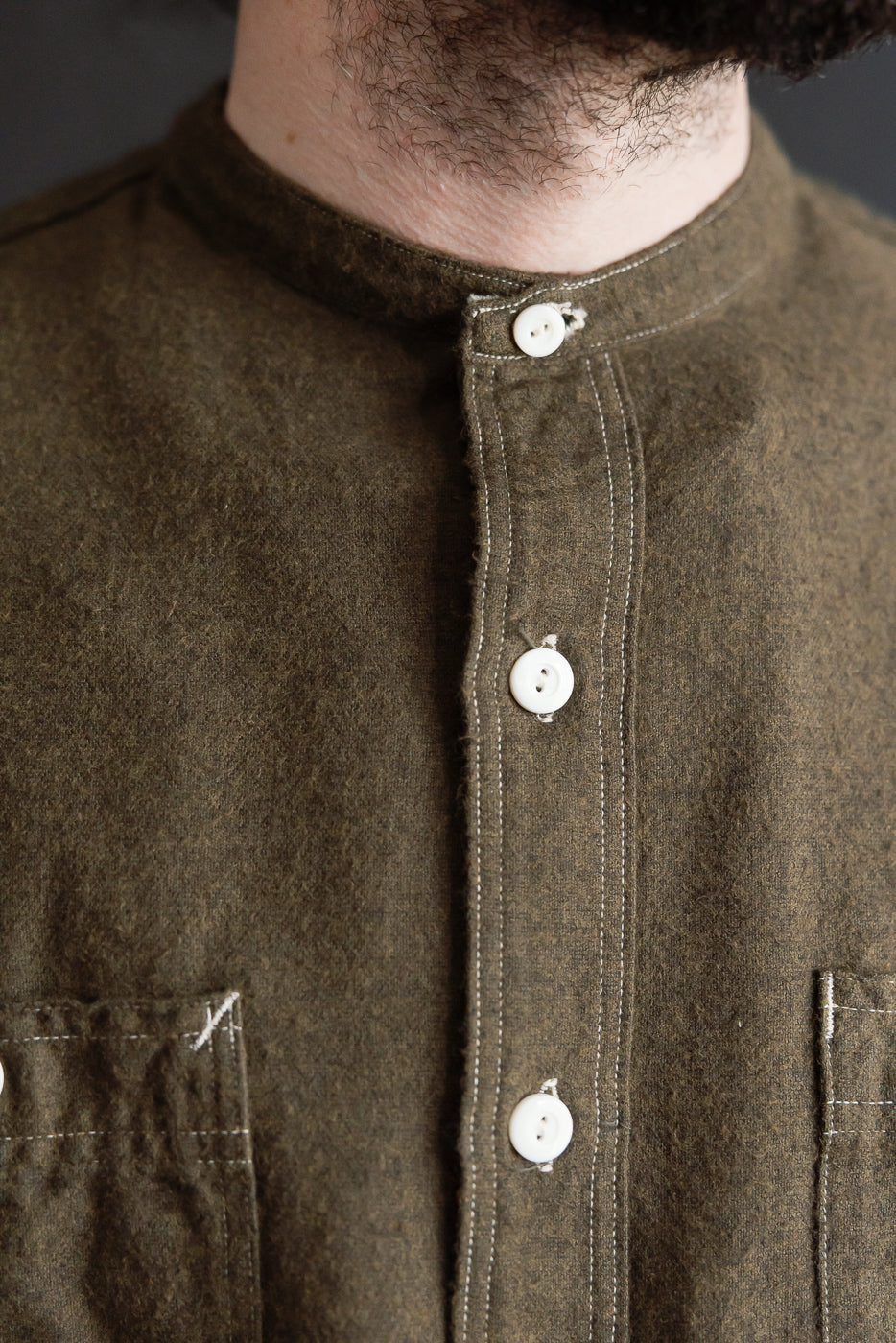 Close-up of front chest and collar on men's tobacco cotton heather flannel shirt, band collar and white buttons, worn by male model 5'9