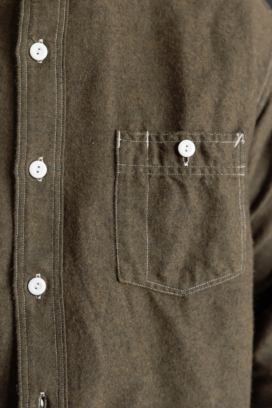Close-up of front left chest pocket and buttons on tobacco cotton flannel shirt, showing fabric texture and stitching details.