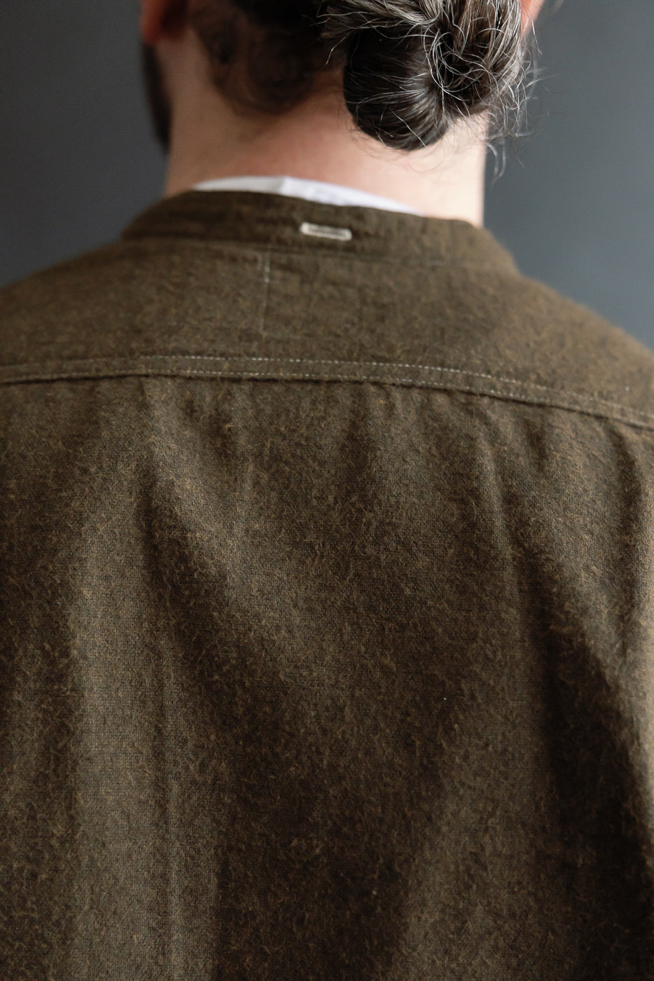 Close-up of the back upper section of a brown heather flannel shirt on male model, showing fabric texture and collar detail, Dant contemporary casual apparel.