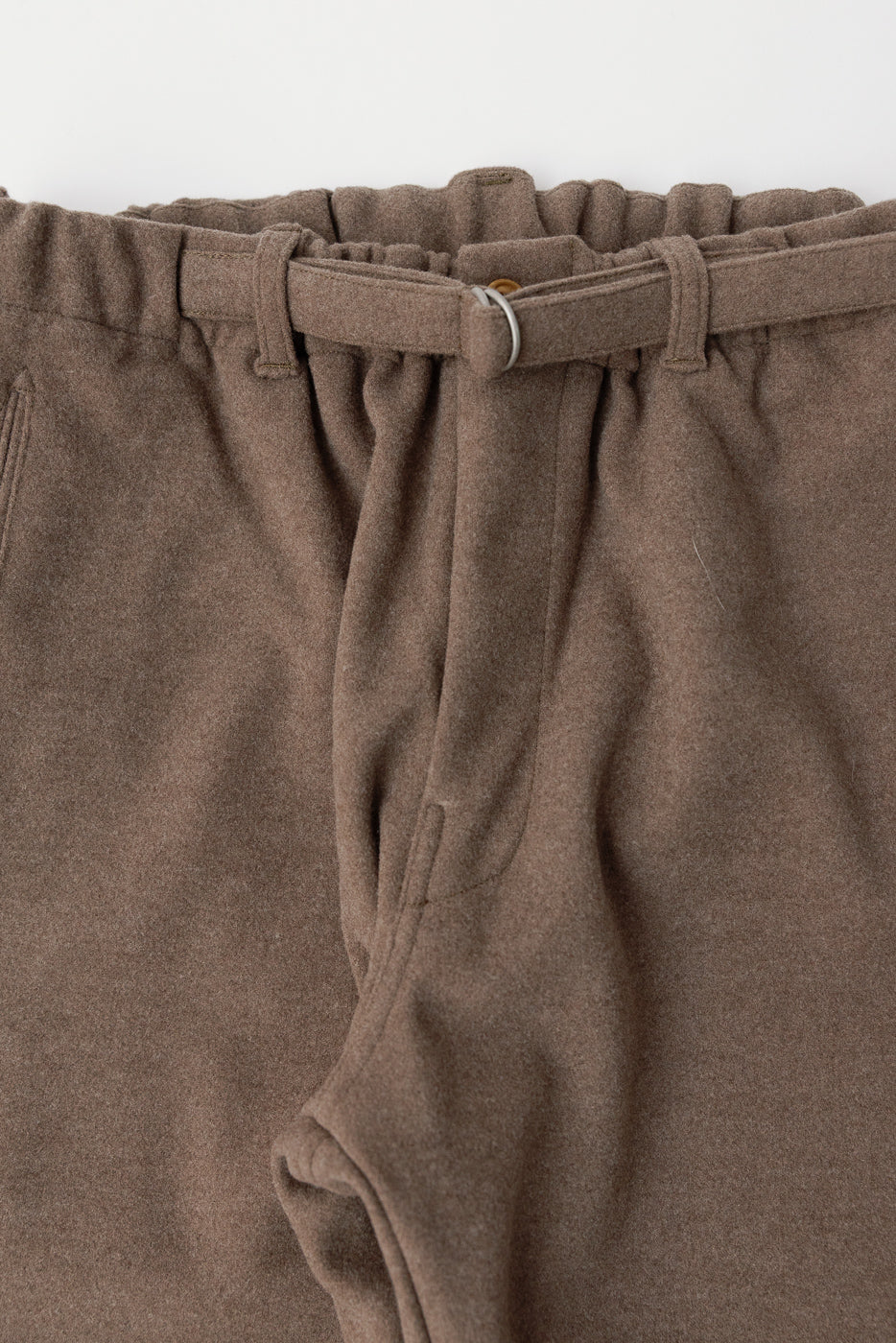 Close-up front view of brown sweatpant waist, showing belt, fabric texture, and pockets.