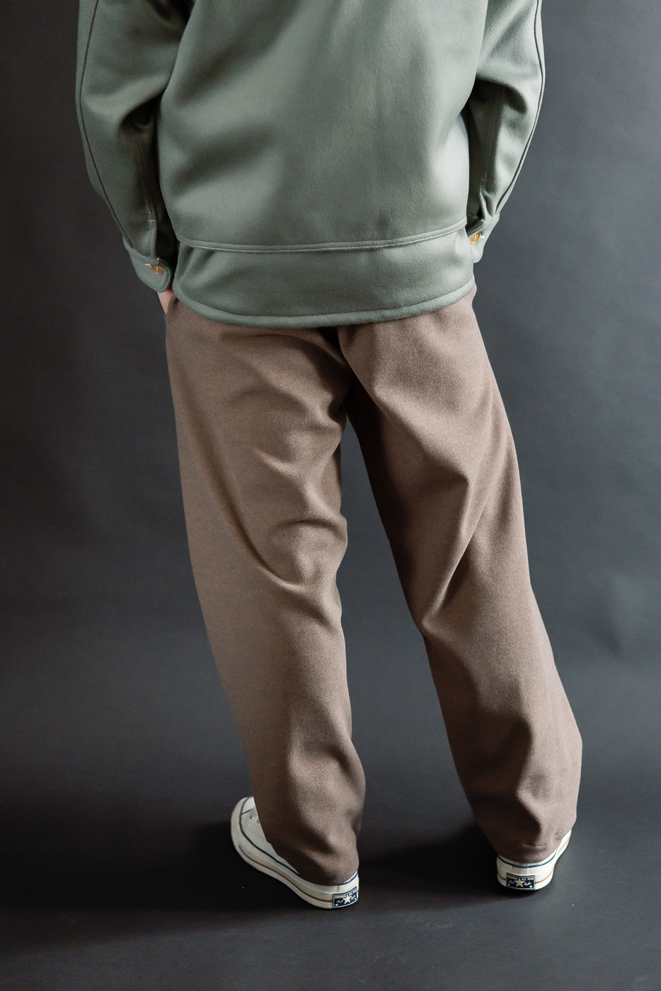 Back view, full-body of male model 5'9 165lbs in brown sweatpants, casual setting