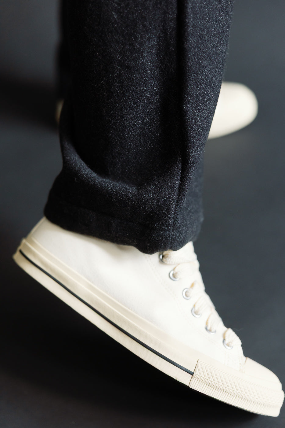 Close-up of basket tweed pant hem in charcoal on male model, side view with sneakers