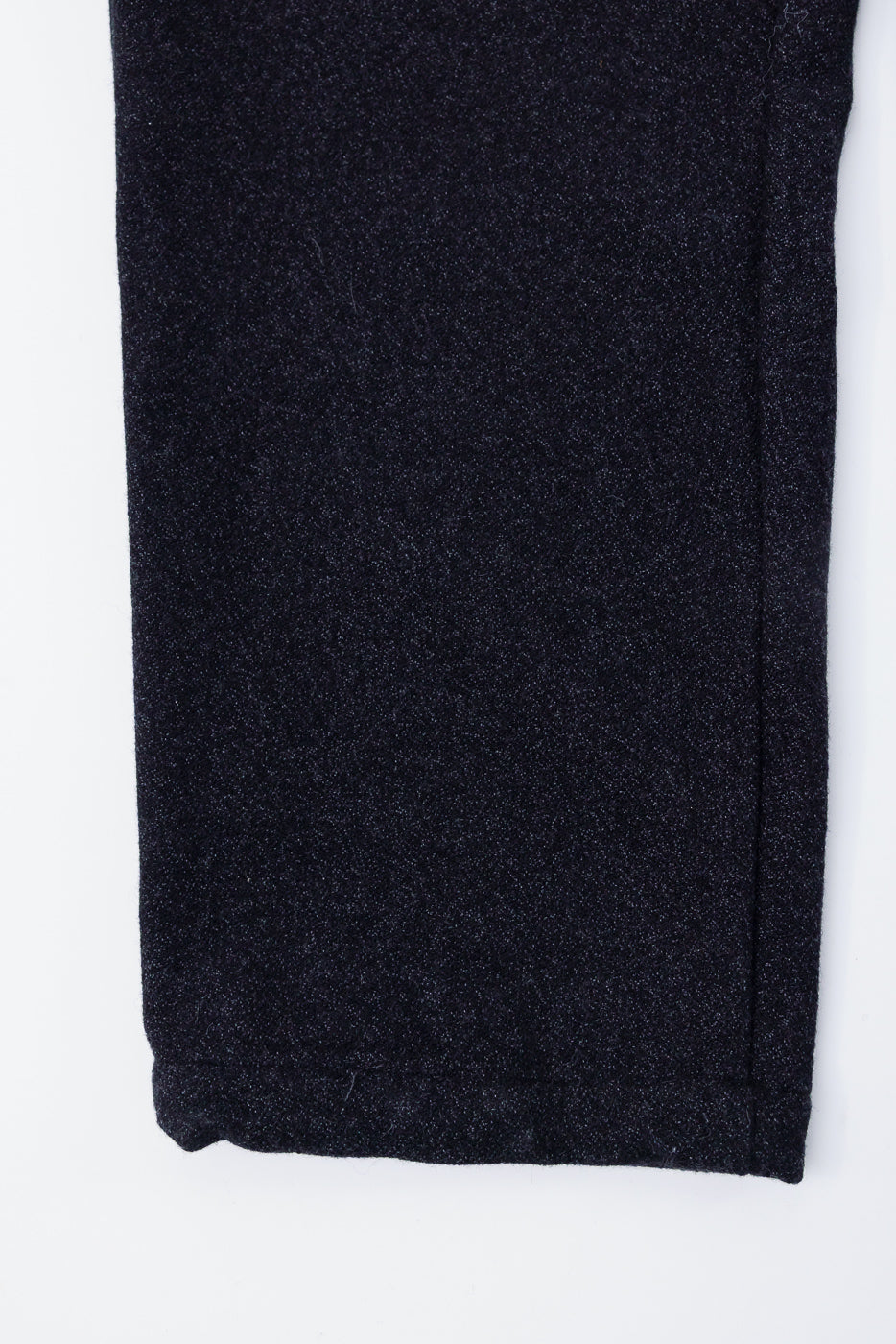 Close-up of front lower leg and hem on charcoal basket tweed pants, showing fabric texture.