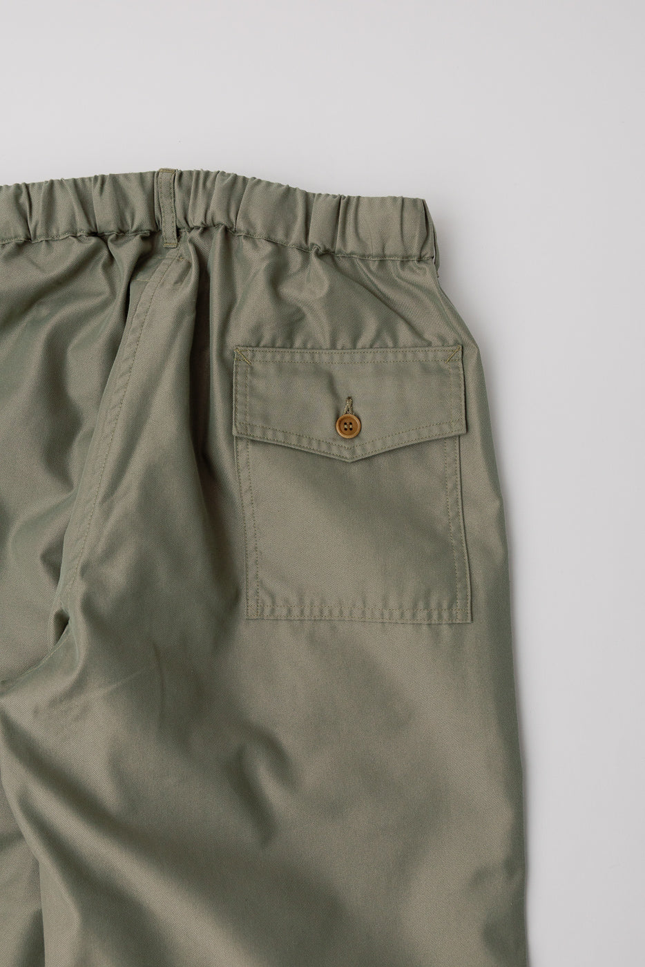 Close-up of khaki French twill pants back, showing elastic waistband and buttoned pocket detail