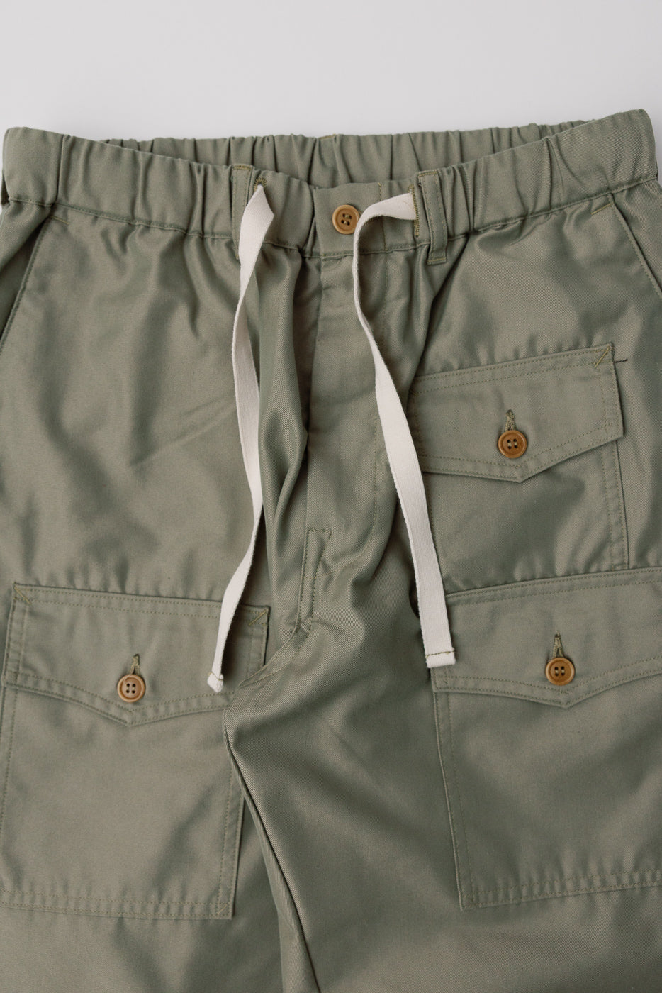 Close-up front view of khaki French twill pants with drawstring waist and button pockets