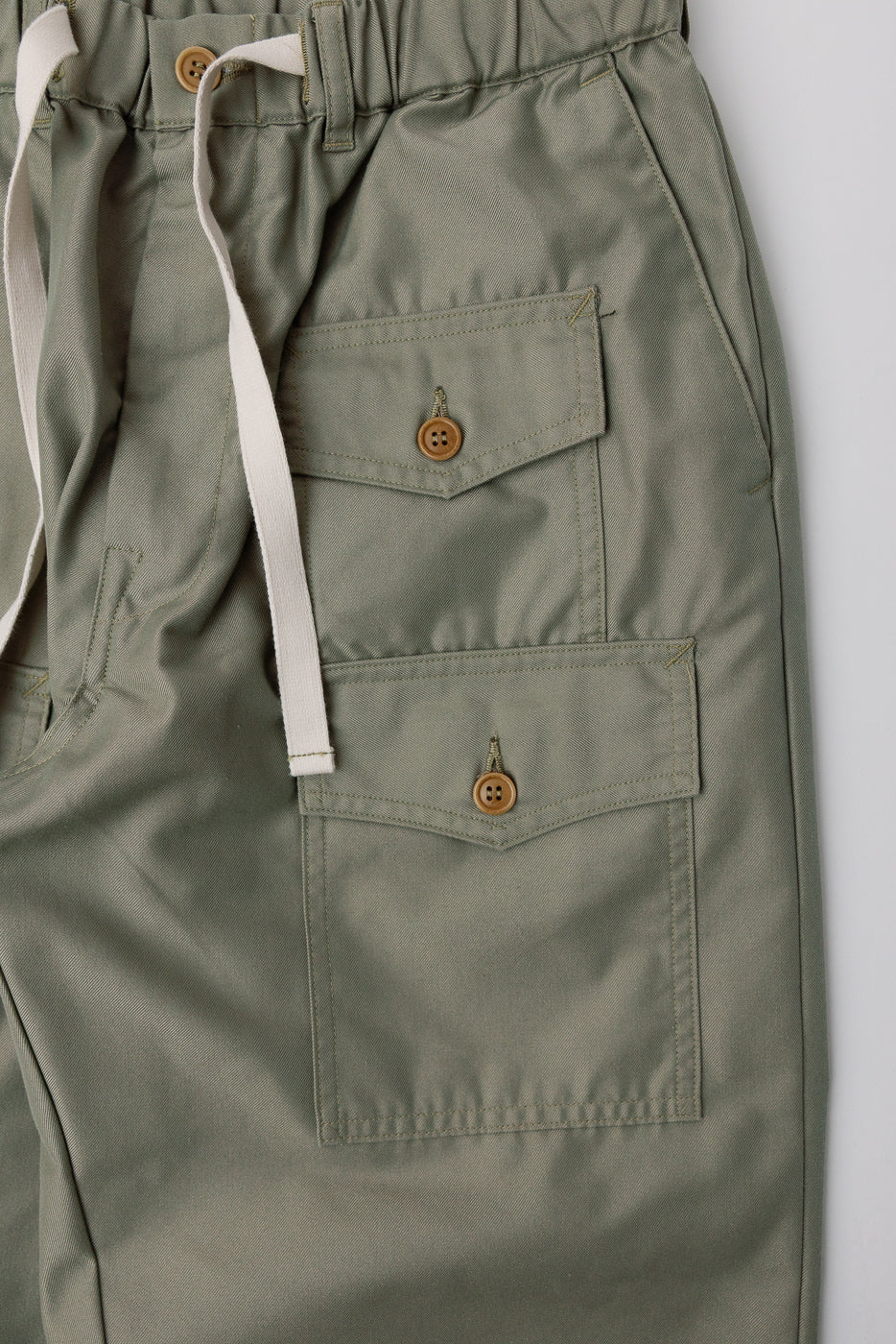 Close-up of Post O'Alls Town and Country khaki French twill pants front side, showing buttoned flap pockets, drawstring waistband, and fabric texture from Dant contemporary apparel.