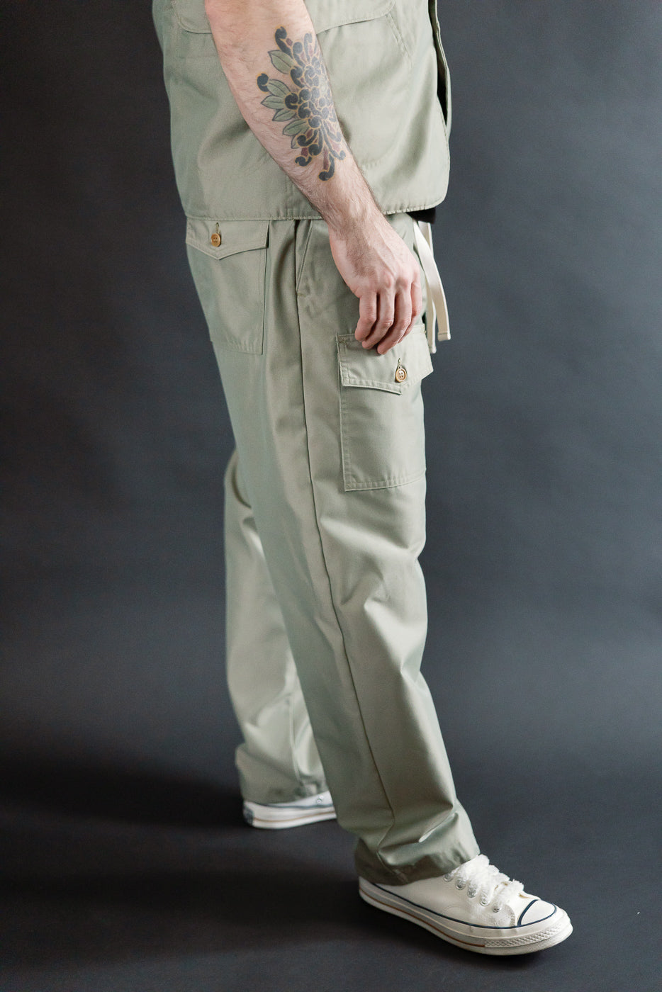 Side view close-up of Post O'Alls Town and Country khaki French twill pants on 5'9 athletic male model, highlighting side cargo pocket and button details.