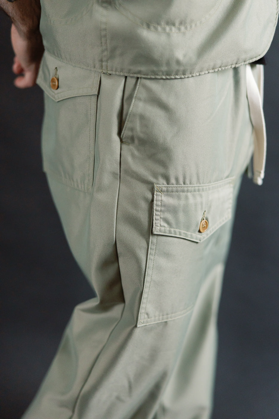 Close-up side view of khaki Post O'Alls French twill pants on male model, showing pockets and button detail