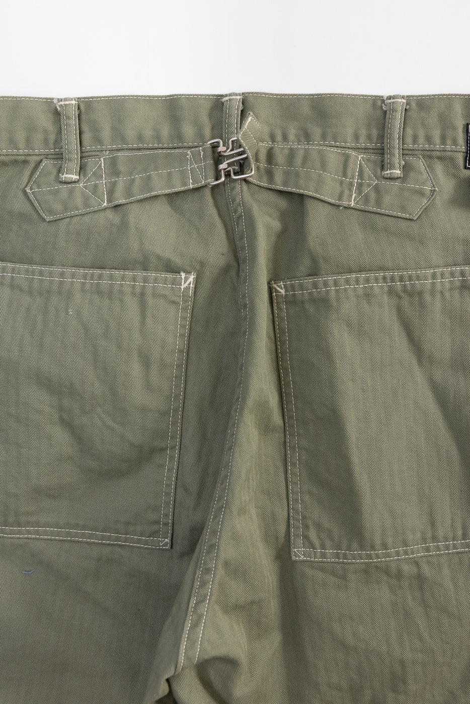 Close-up of back waist and pockets of sage green herringbone shorts with back cinch detail.