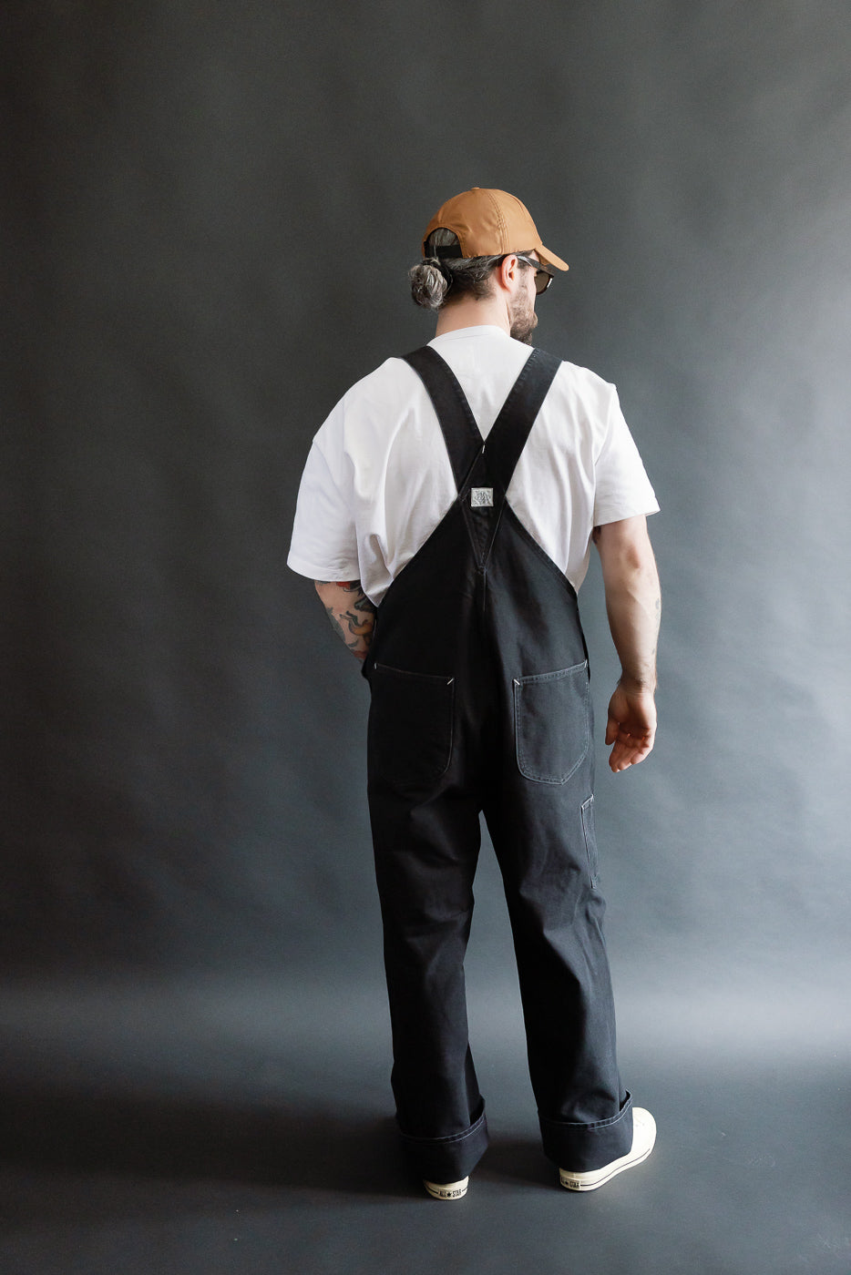 Male model 5'9 165lbs athletic build, full body rear view, black canvas overalls, Dant