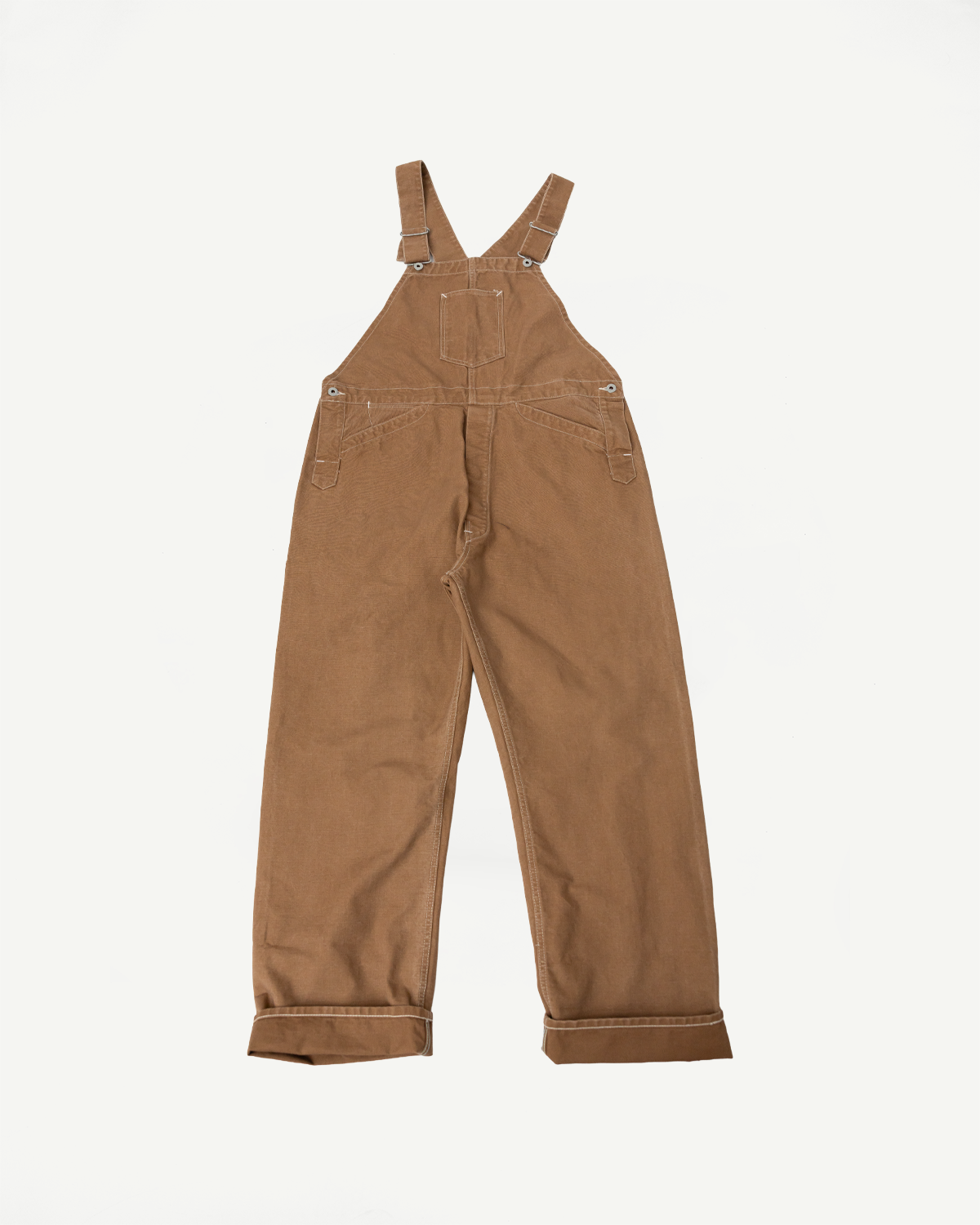 Flat lay of brown canvas overalls, back view, showing straps and pockets, casual workwear