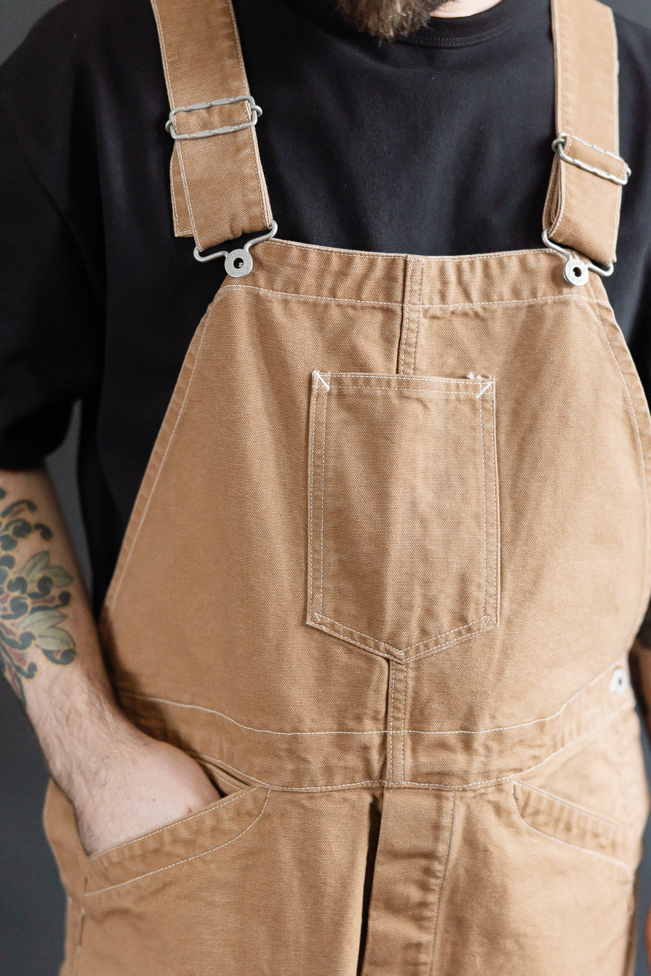 Close-up front view of brown canvas overalls on male model, 5'9