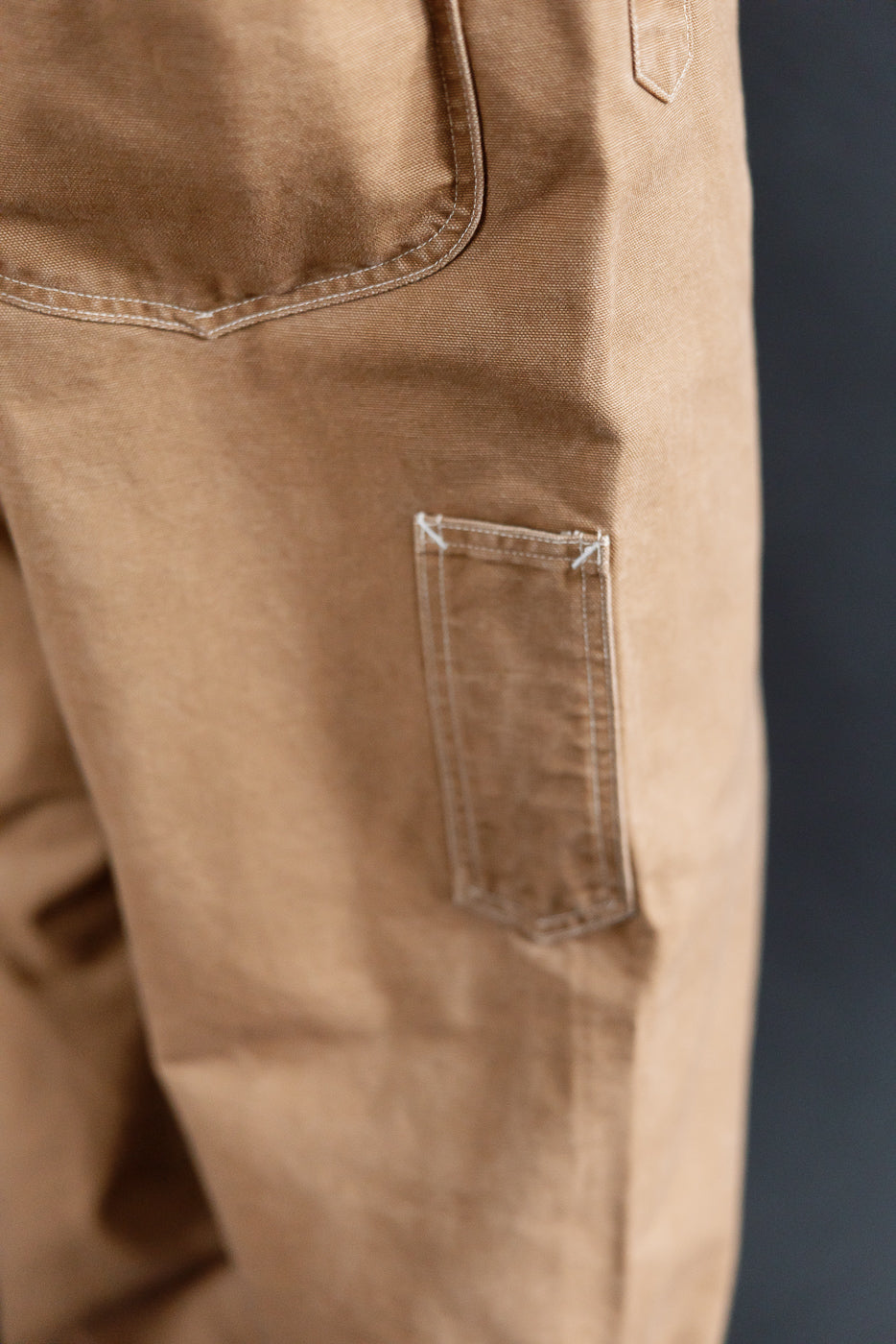 Close-up of Post 46 overalls washed brown canvas, side pocket detail and fabric texture