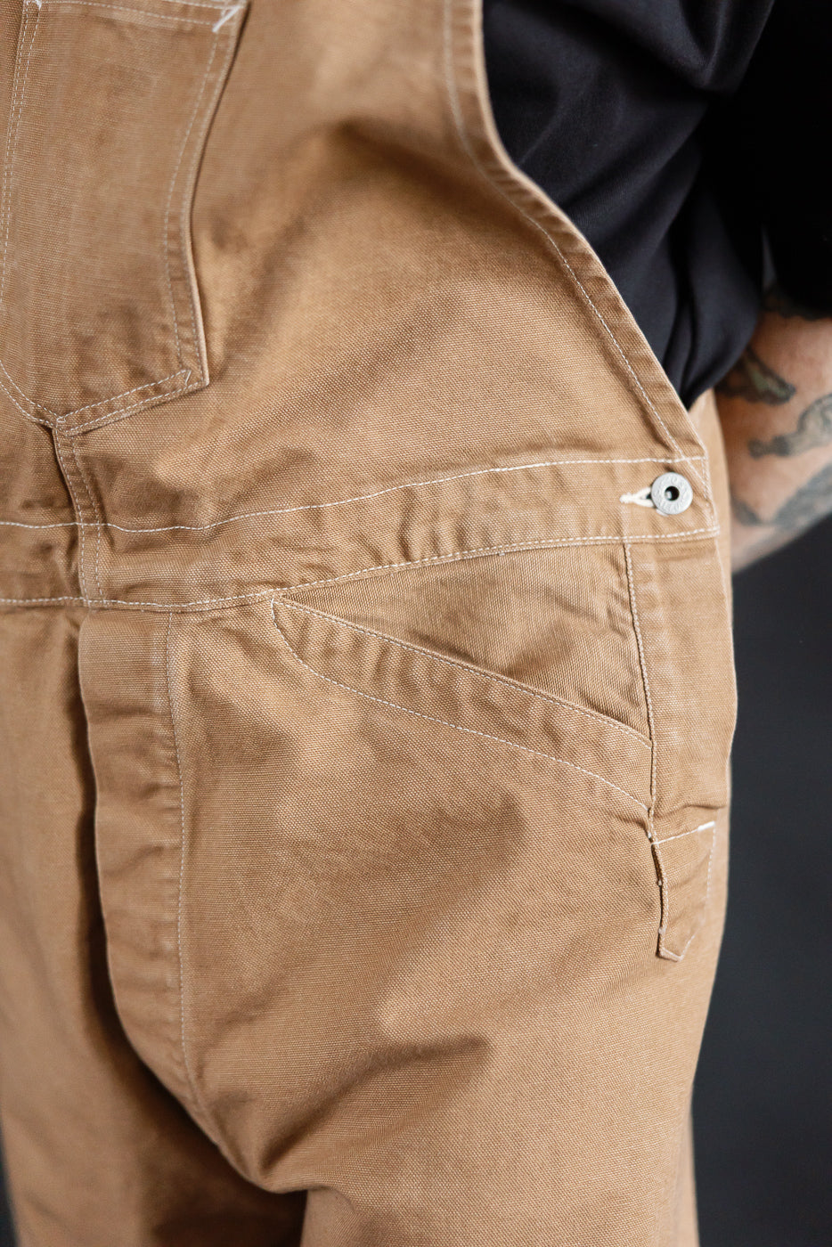 Close-up of washed brown Post O'Alls Post 46 overalls, back side pocket detail, on male model 5'9