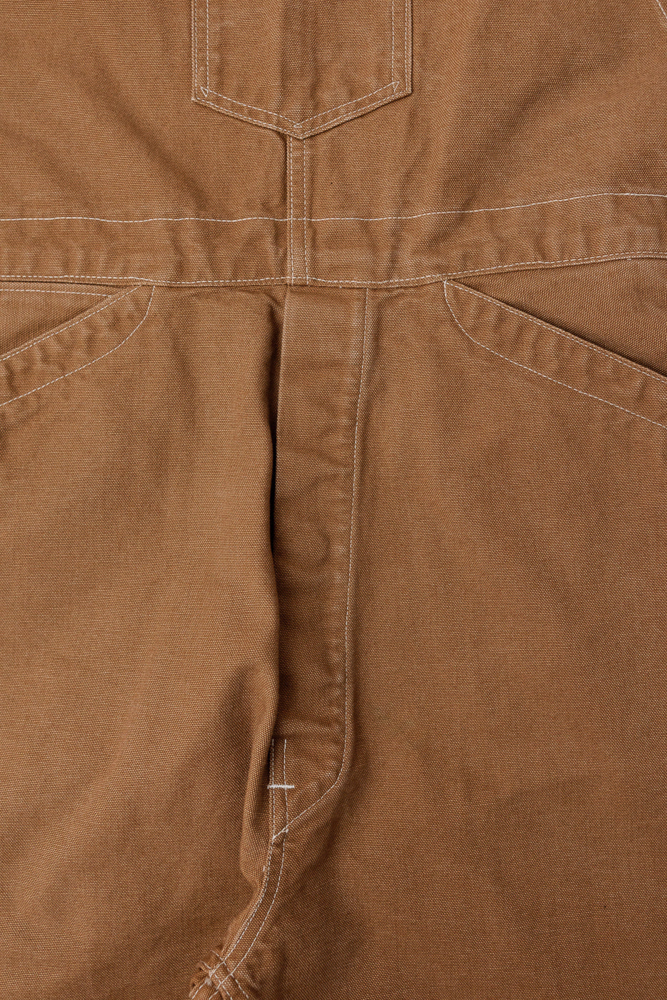 Close-up of back waist and pocket stitching on brown pigment-dyed canvas overalls, back view.
