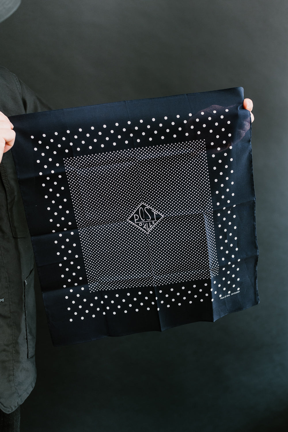 Close-up of Post O’Alls navy bandana with white polka dots and logo, flat front view.