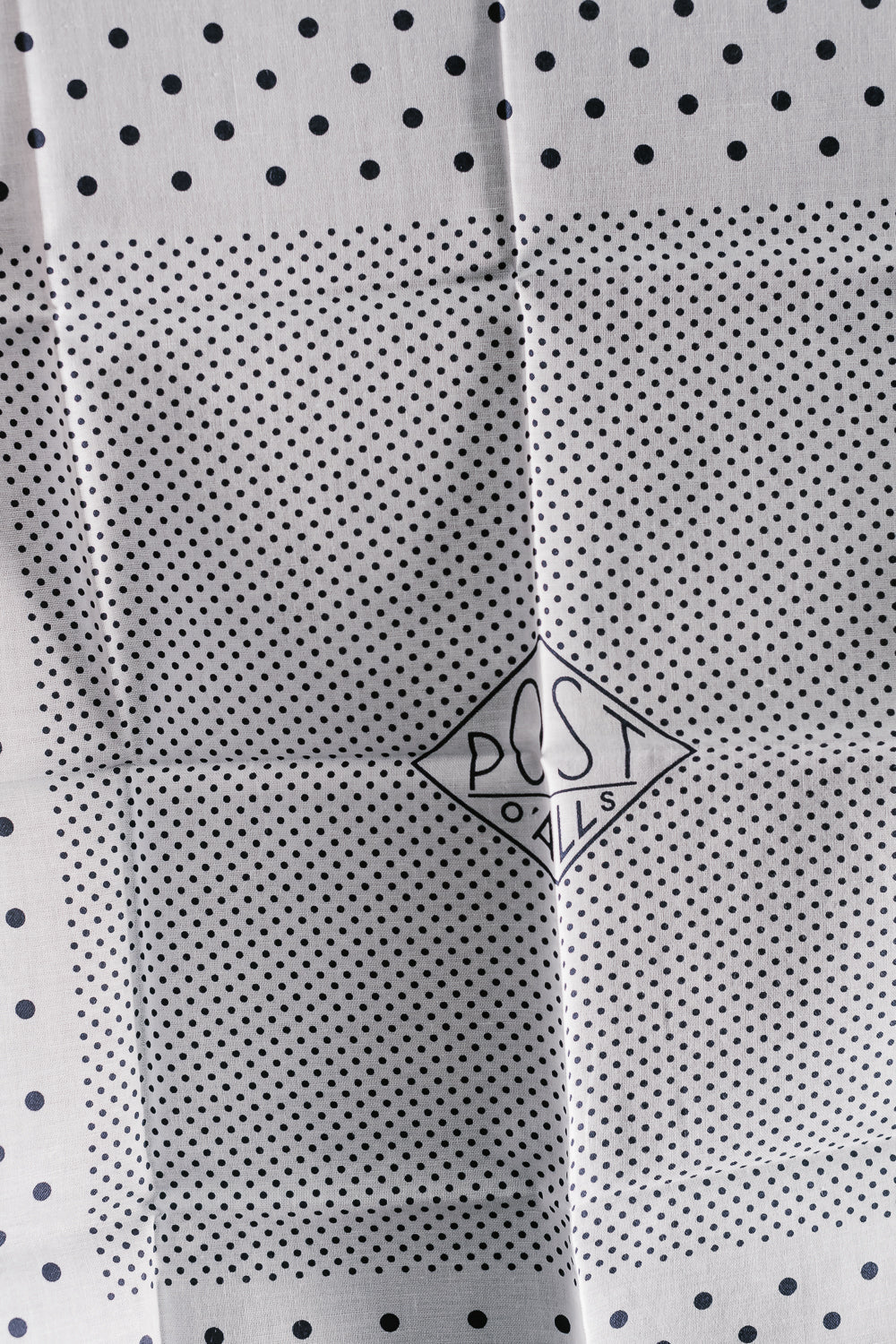 Close-up of Post O'Alls white bandana hankie, front side with black dot print and logo detail.