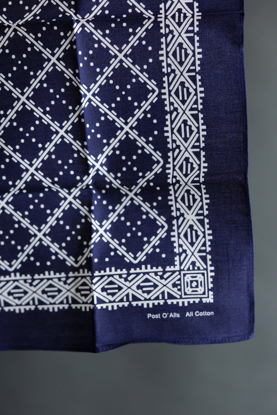 Close-up of navy Post O’Alls cotton bandana, front side showing white stitched geometric design.
