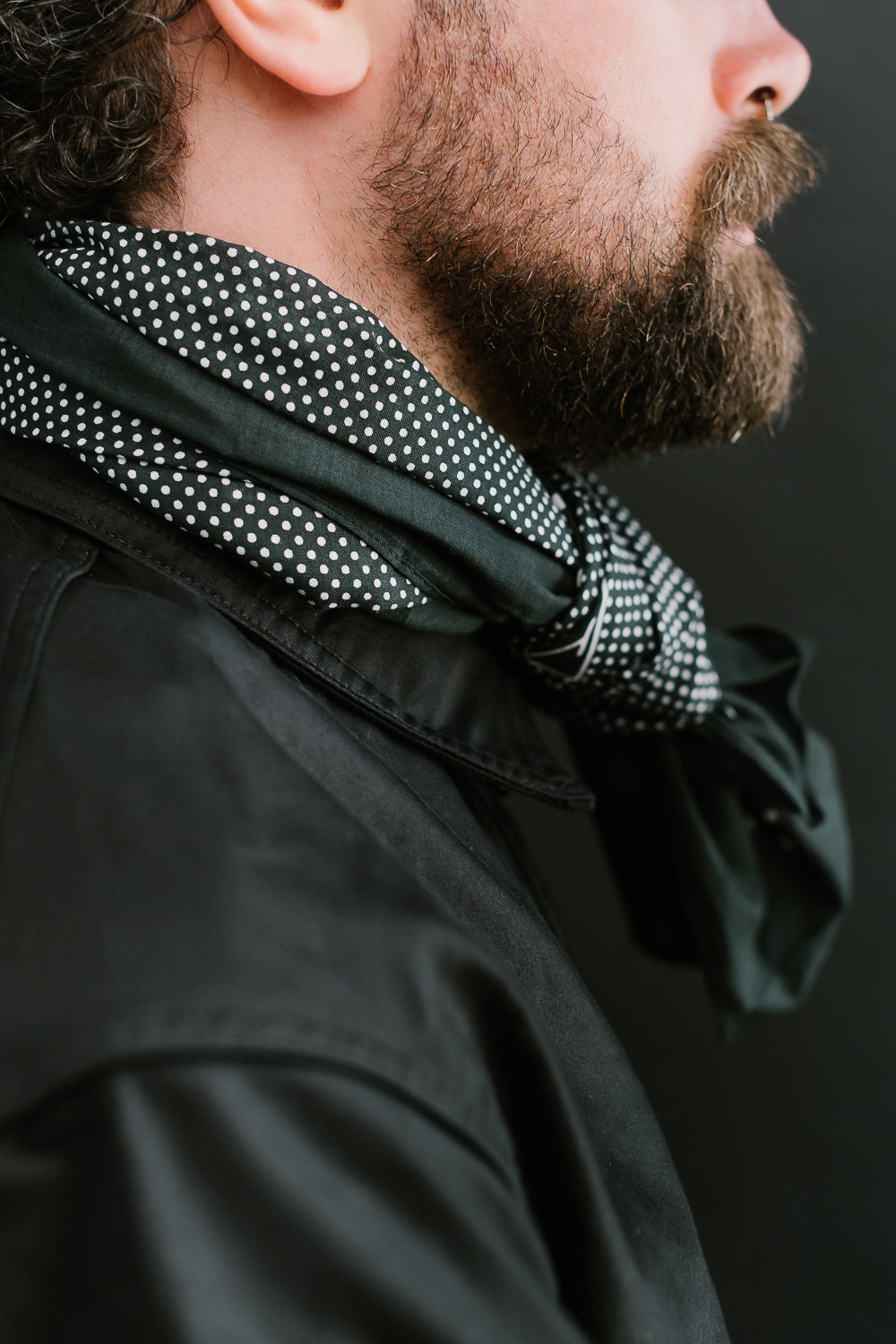 Close-up right side of charcoal polka dot bandana scarf on male model, 5'9