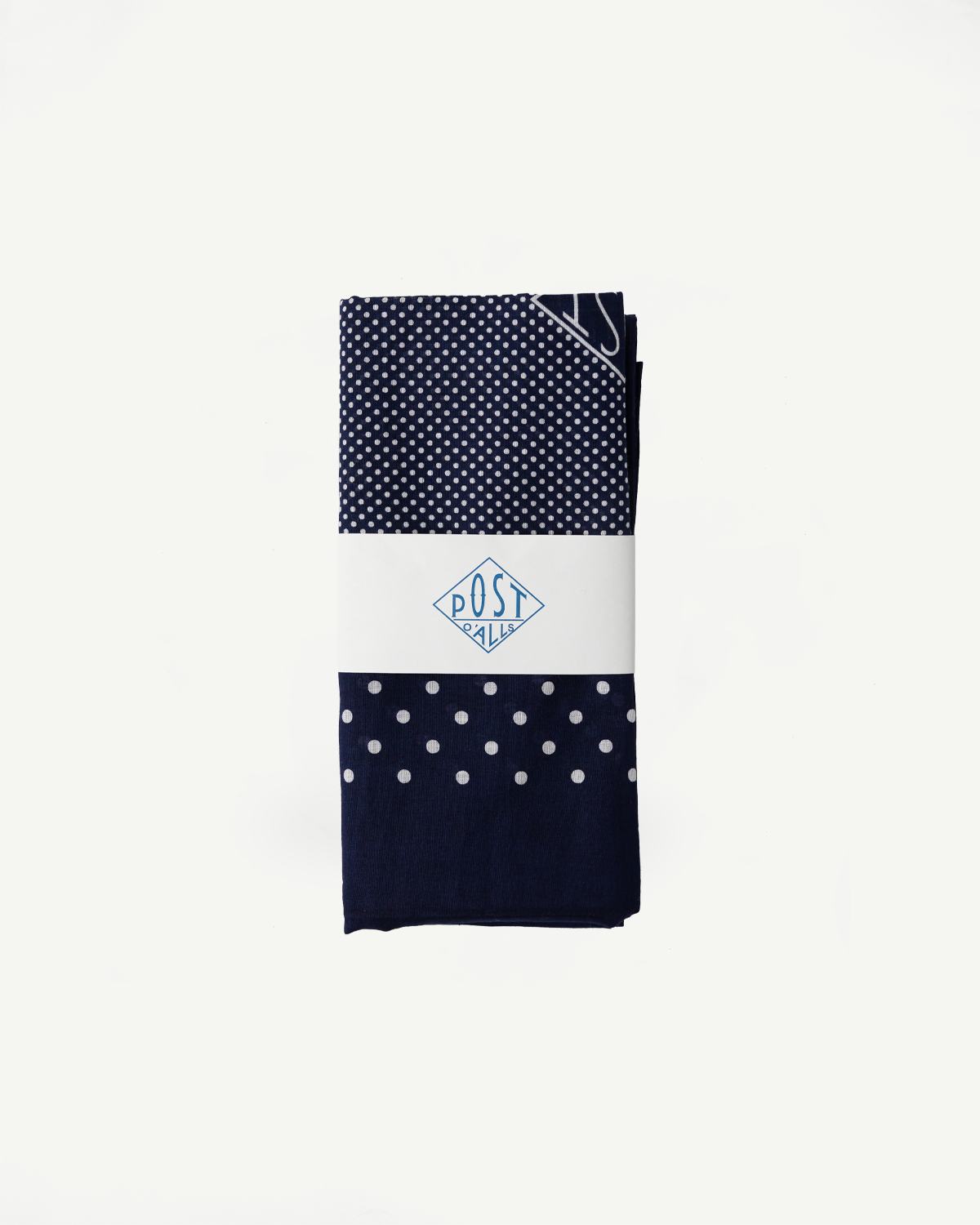 Flat lay front view of navy Post O’Alls bandana scarf with polka dot pattern, folded with brand paper wrap.