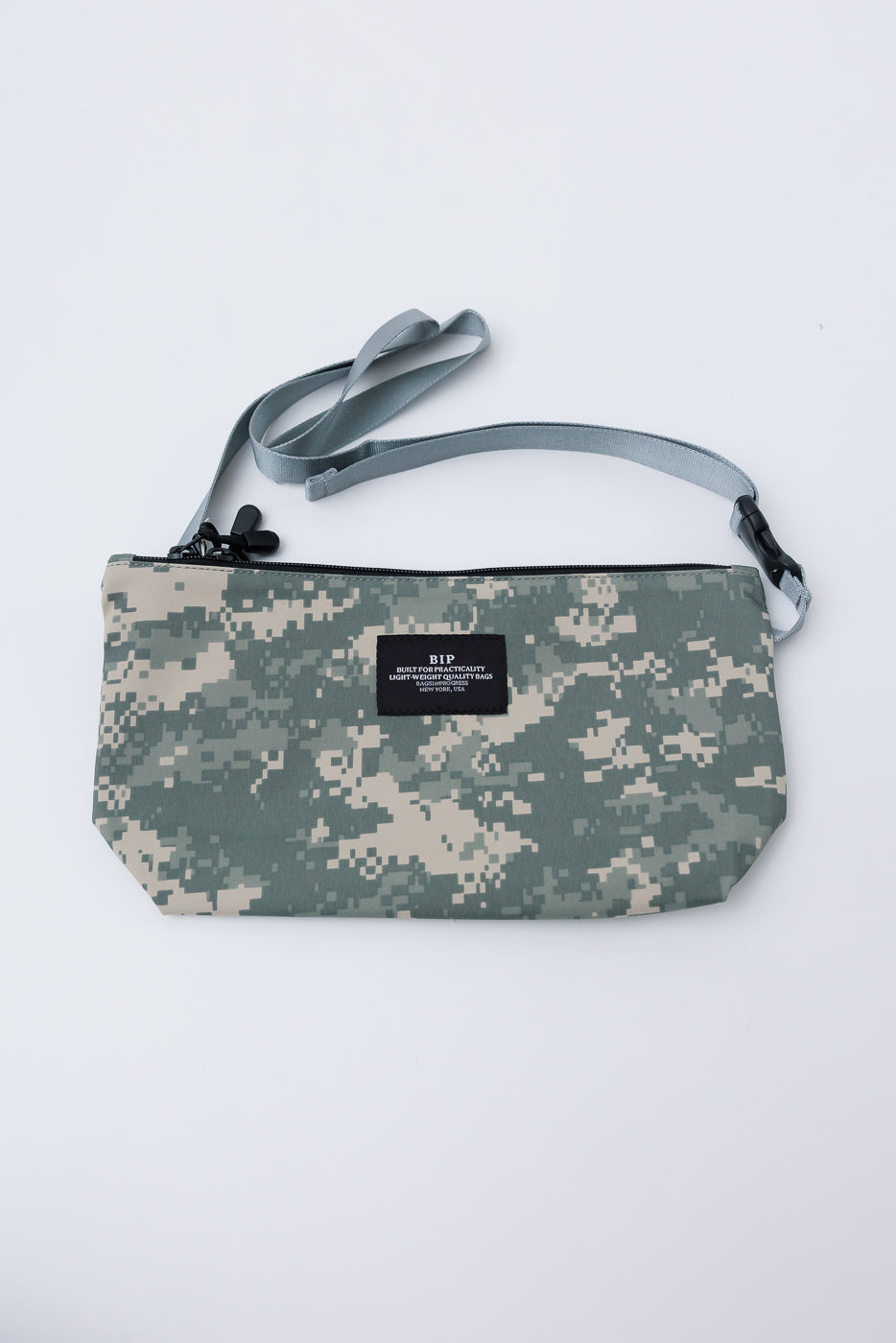 Flat lay of digital camo desert crossbody fanny pack, front view, zipper and logo tag visible.