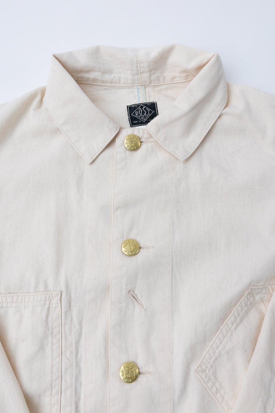 3102SB-MDN - Sweetbear 3 Mid Weight Denim - Natural: Off-white cotton chore jacket with brass-tone buttons, a relaxed shirt collar, and a distinctive crooked chest pocket, showcasing Post O'Alls’ vintage-inspired design.