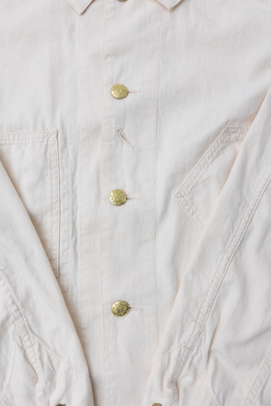 Close-up of the 3102SB-MDN Sweetbear 3 Mid Weight Denim Jacket, showcasing brass buttons, slanted pockets, and a glimpse of the relaxed collar in light-cream canvas, embodying vintage American workwear style.