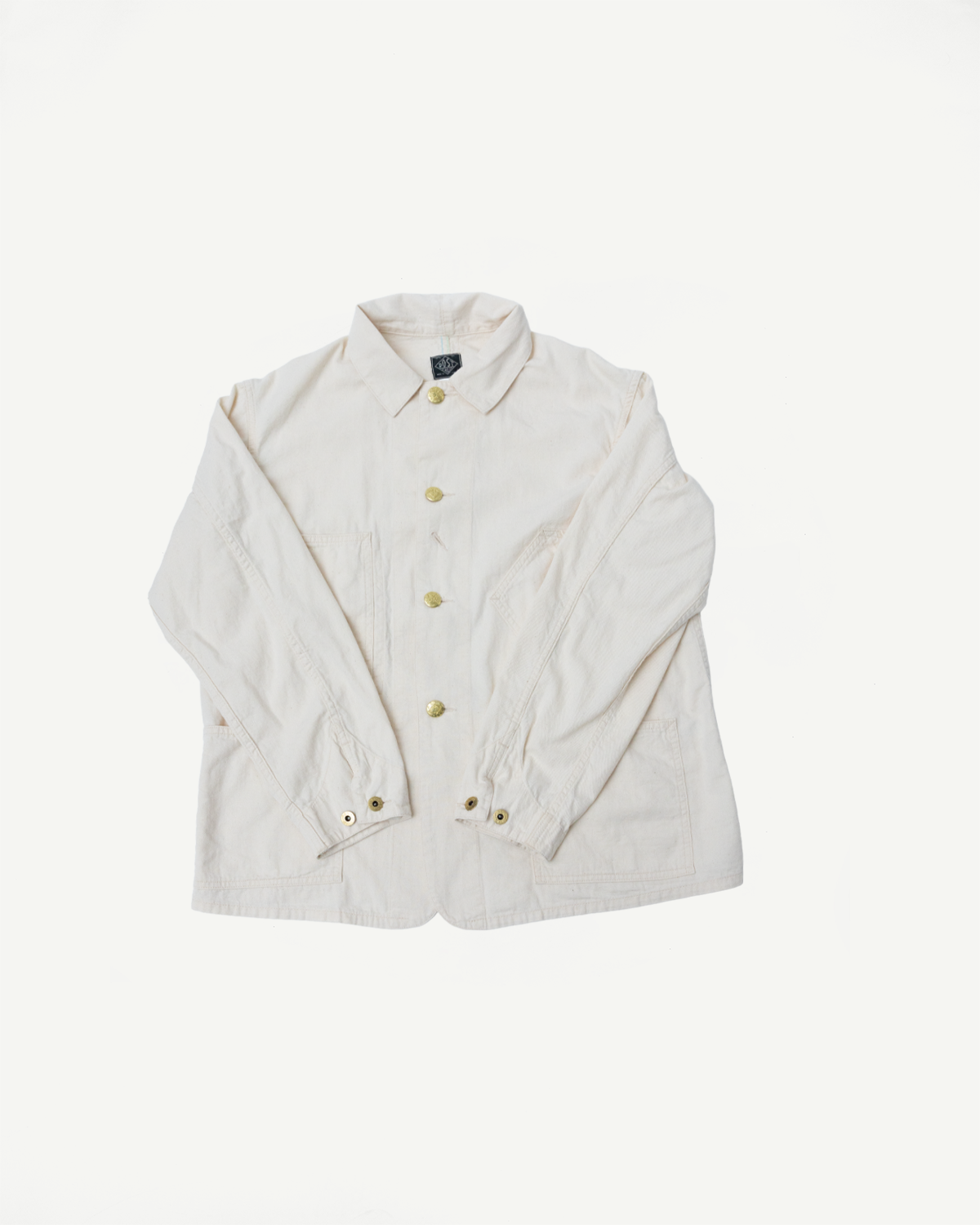 Flat lay, front view of natural mid-weight denim jacket, showing buttons, collar, and front pockets.