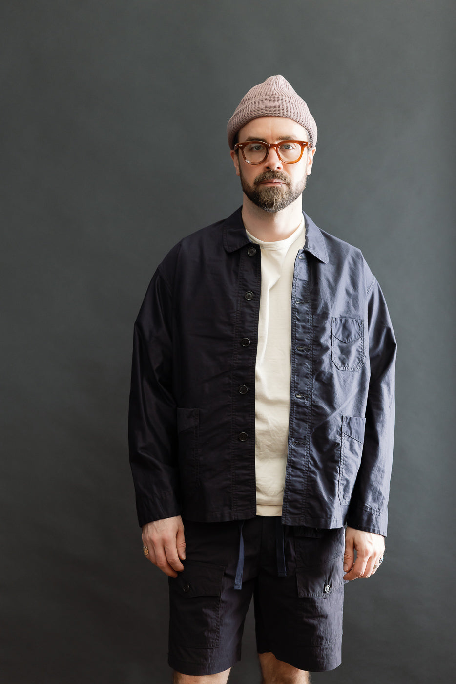 A bearded man models the 3135-LMN Post Chinois Travail 2 Light Moleskin jacket in dark navy, showcasing its relaxed, cropped fit and patch pockets, embodying a fusion of French-Chinese workwear.