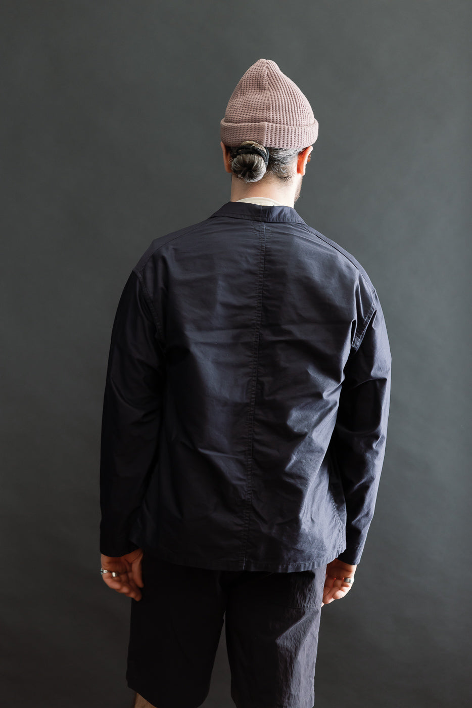 A person models the 3135-LMN - Post Chinois Travail 2 Light Moleskin jacket in dark navy, showcasing its relaxed fit and rounded collar, embodying a blend of French-Chinese workwear aesthetics.