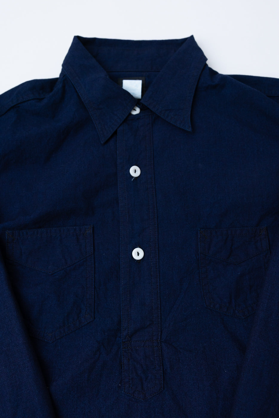 Close-up front view of dark indigo vintage sheeting shirt, showing collar, button placket, and chest pockets.