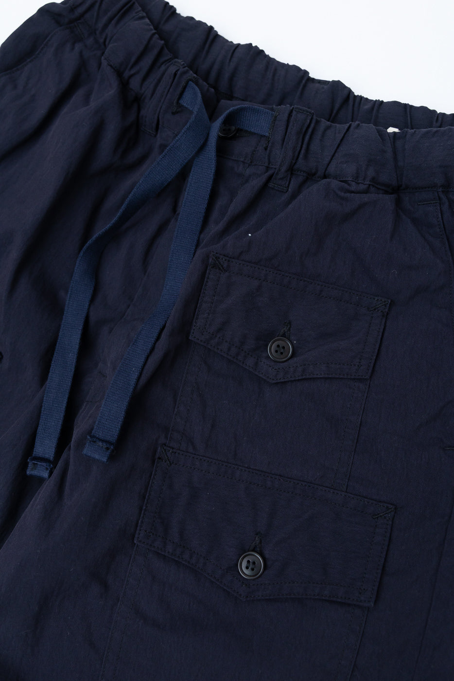 Close-up front view of navy twill shorts, showing drawstring waist and buttoned flap pockets.
