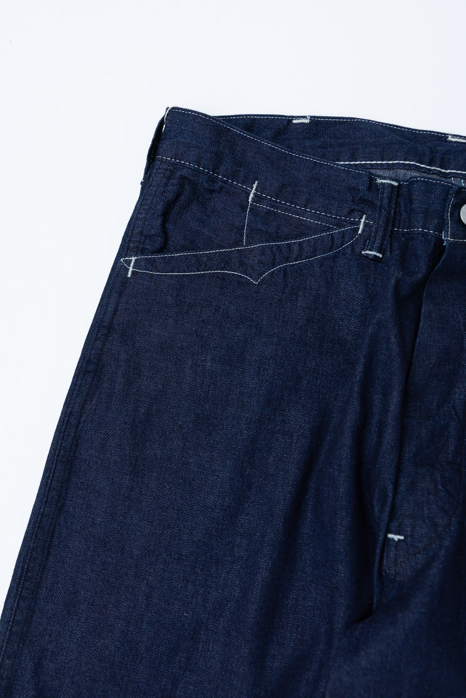 Close-up of front left side of dark indigo denim jeans showing pocket and stitching details.