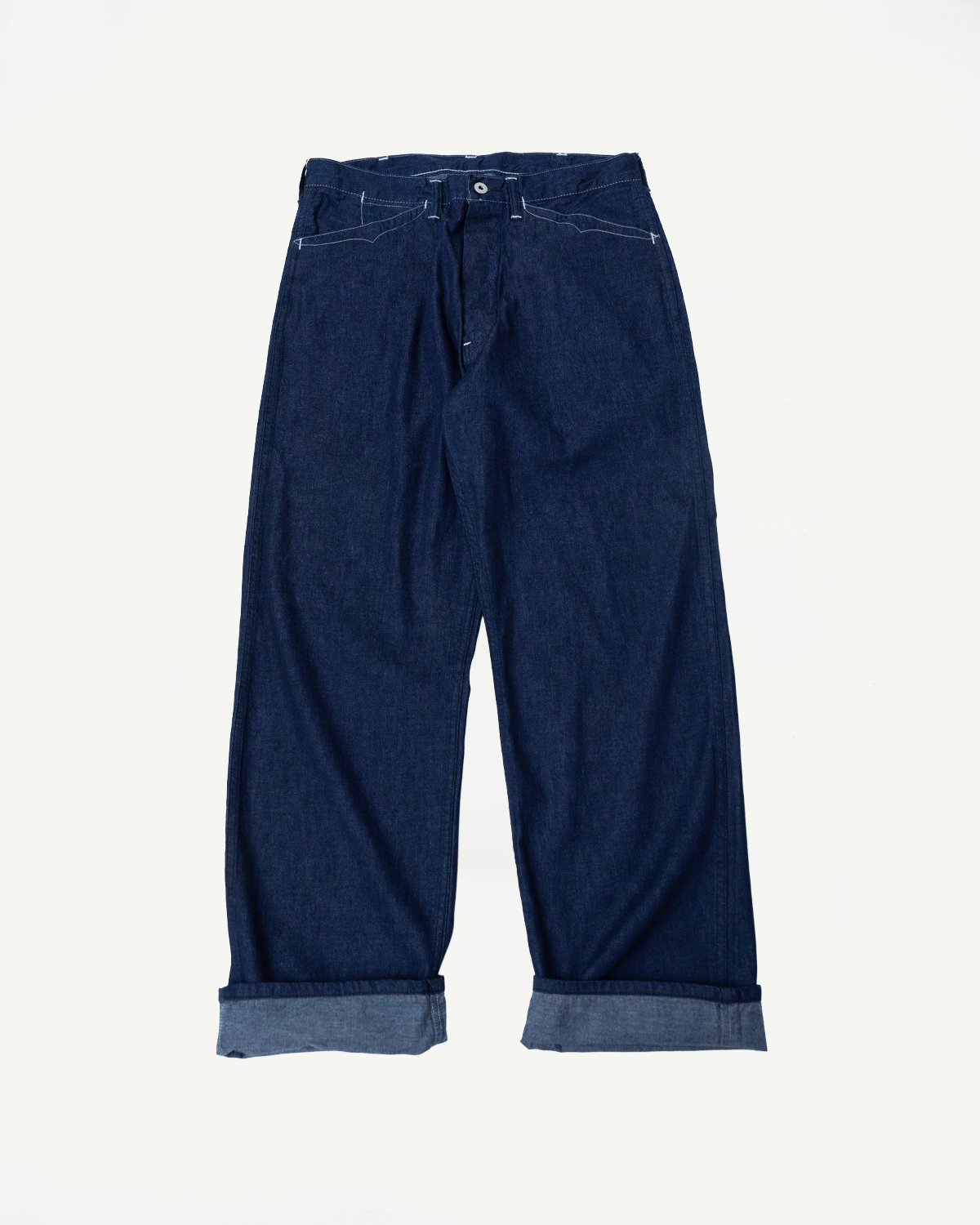 Flat lay, front view of dark indigo denim pants with cuffed hems and button fly detail.