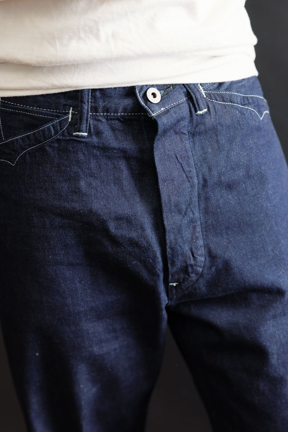 Close-up front view of dark indigo denim jeans on a male model, 5'9