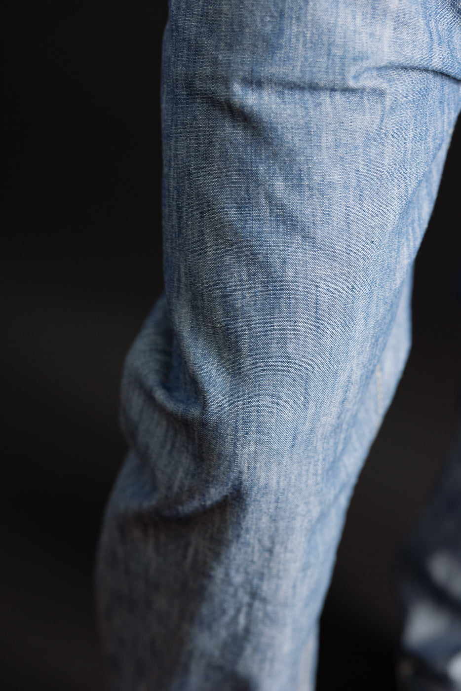 Close-up of the side texture and denim fabric of light blue jeans.