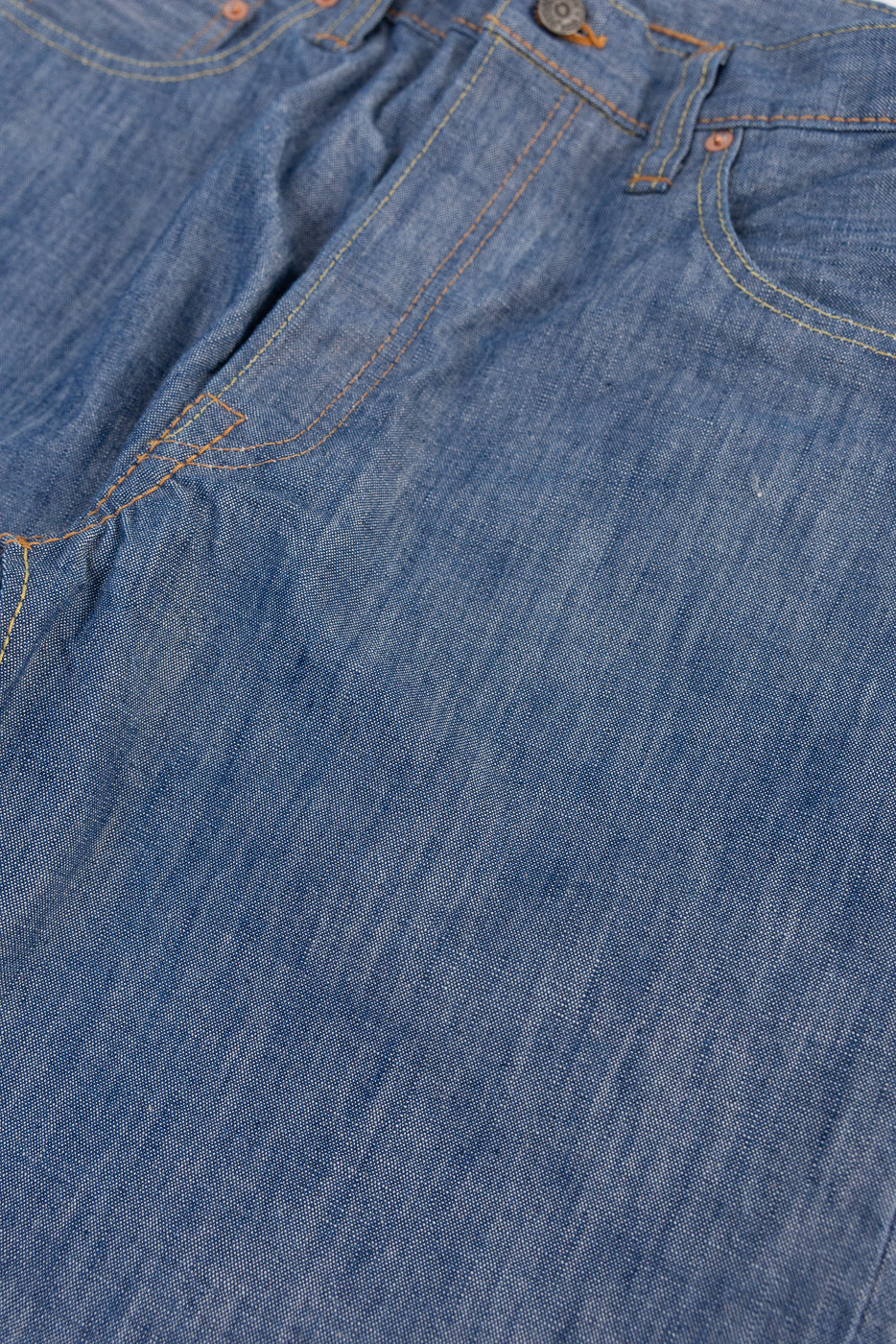 Close-up front view of blue denim fabric texture and waistband with orange stitching.