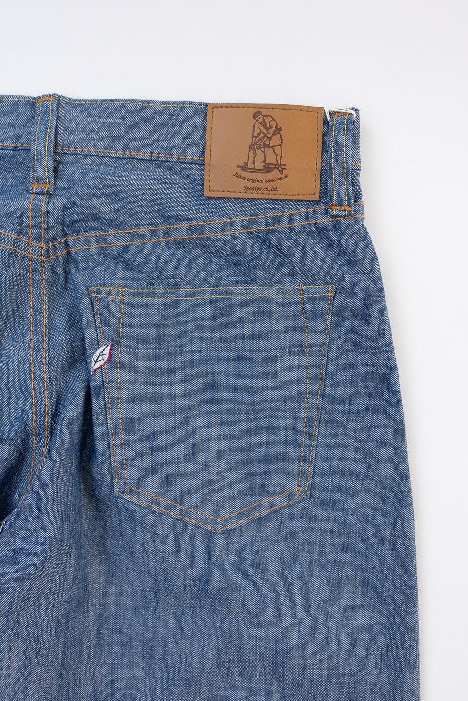 Close-up of back right pocket and leather waist patch on blue denim jeans.