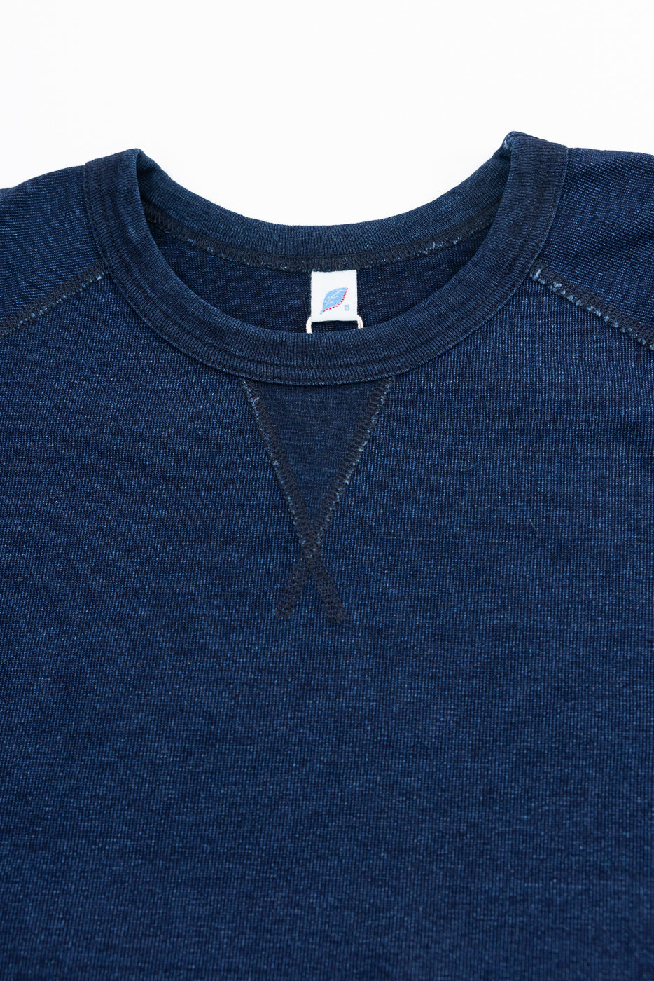 Close-up front view of navy raglan sweatshirt showing ribbed crew neck, tag, and textured fabric