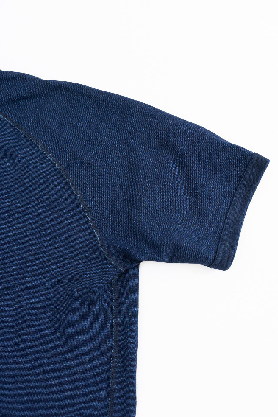 Close-up front view of dark blue selvedge t-shirt sleeve, showing ribbed hem and shoulder seam detail