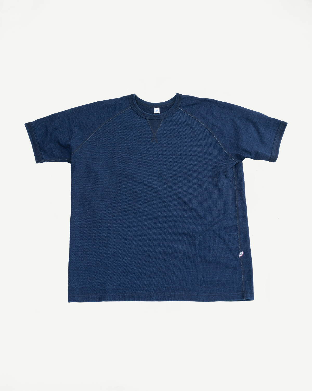 Flat lay front view of navy blue ribbed cotton t-shirt with raglan sleeves, crew neck, and side seam tag detail