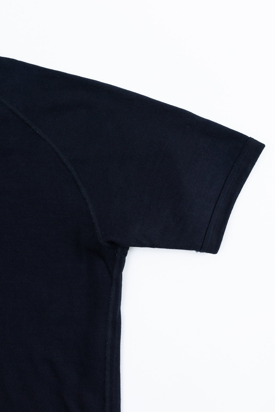 Close-up of navy short sleeve tee, front view showing raglan seam and ribbed hem detail