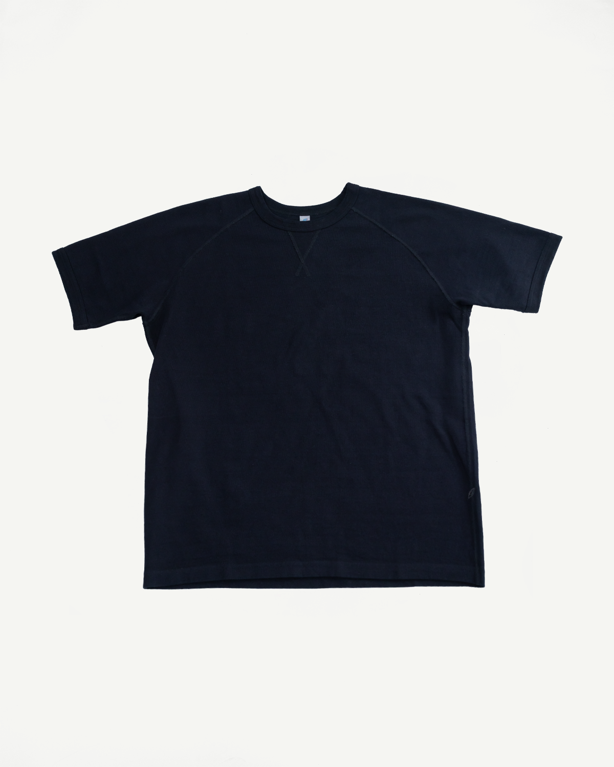 Flat lay front view of navy raglan tee, ribbed crew neck, short sleeves, clean hem, subtle tag detail