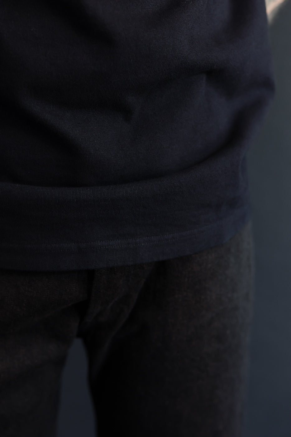Close-up front view of black tee hem on male model, 5'9