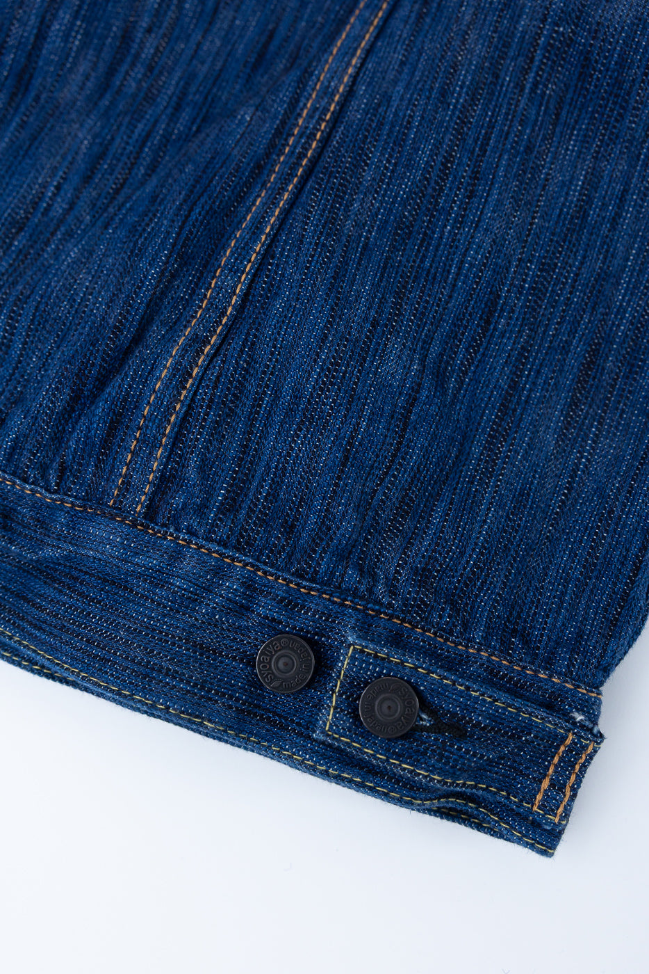 Close-up of the 6225-L - 14.5oz Light Waterfall Selvedge Type II Jacket in Indigo, showcasing the textured blue denim with orange contrast stitching and black metal snap-buttons on the adjustable cuff.