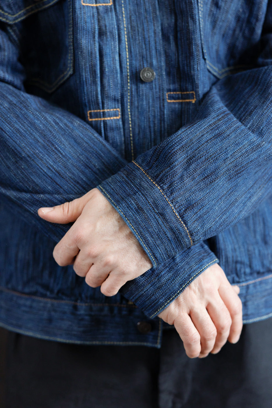 Close-up of the 6225-L - 14.5oz Light Waterfall Selvedge Type II Jacket, showcasing the textured blue denim, buttoned front, contrast stitching, and the wearer adjusting the sleeve.
