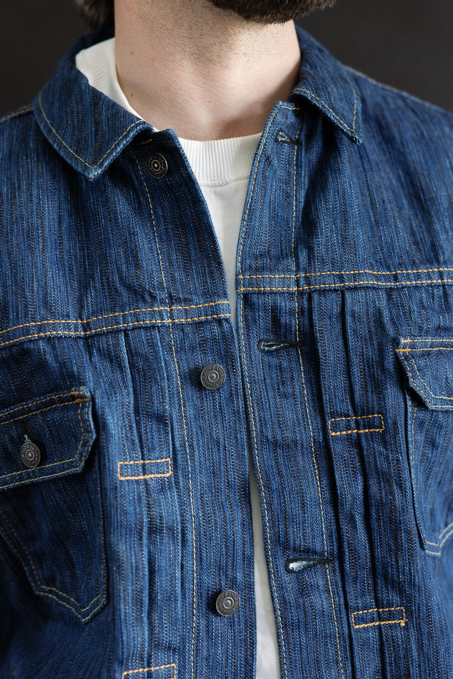Close-up of the 6225-L - 14.5oz Light Waterfall Selvedge Type II Jacket featuring metal snap buttons, contrast stitching, and a white crew-neck shirt underneath, highlighting the textured Japanese selvedge denim.