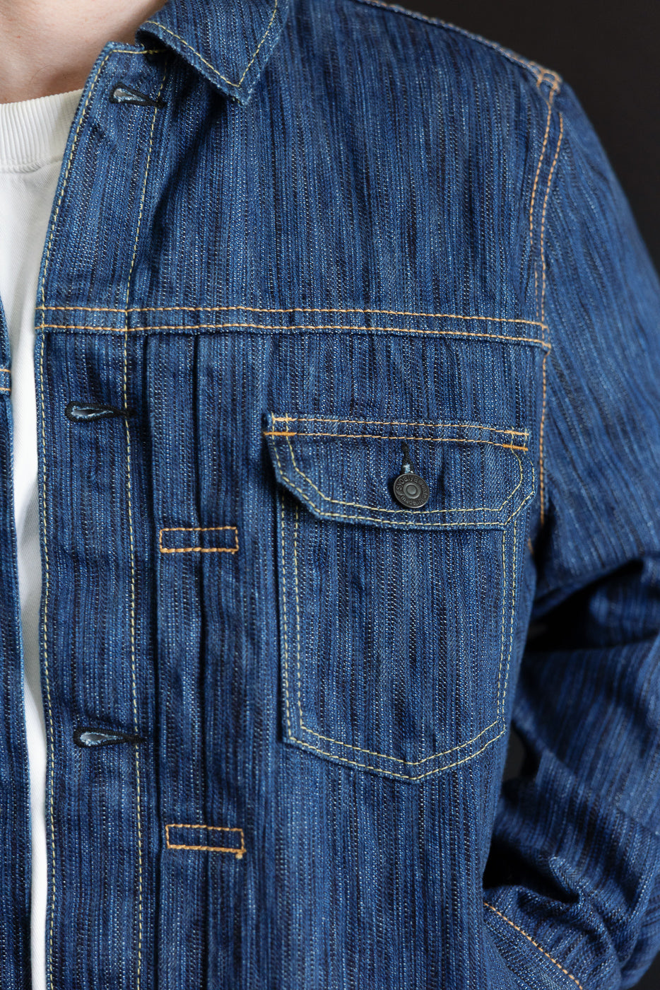 Close-up of the 6225-L - 14.5oz Light Waterfall Selvedge Type II Jacket in indigo, showcasing its left chest pocket with flap and snap-button closure, yellow contrast stitching, and textured denim fabric.