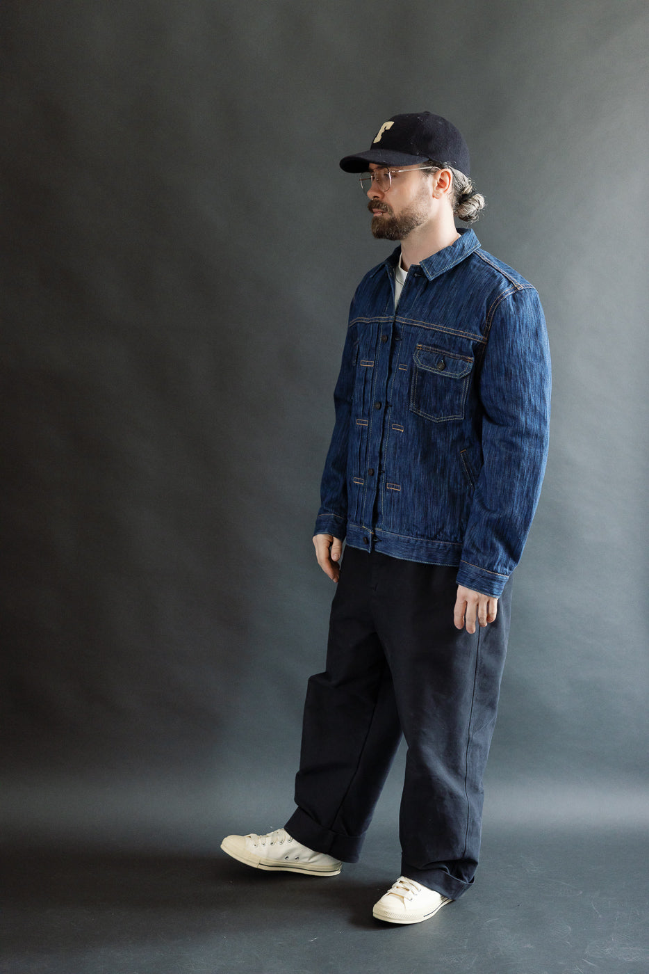 Man wearing the 6225-L - 14.5oz Light Waterfall Selvedge Type II Jacket - Indigo, showcasing its textured Japanese denim and classic silhouette, paired with black trousers and off-white sneakers.